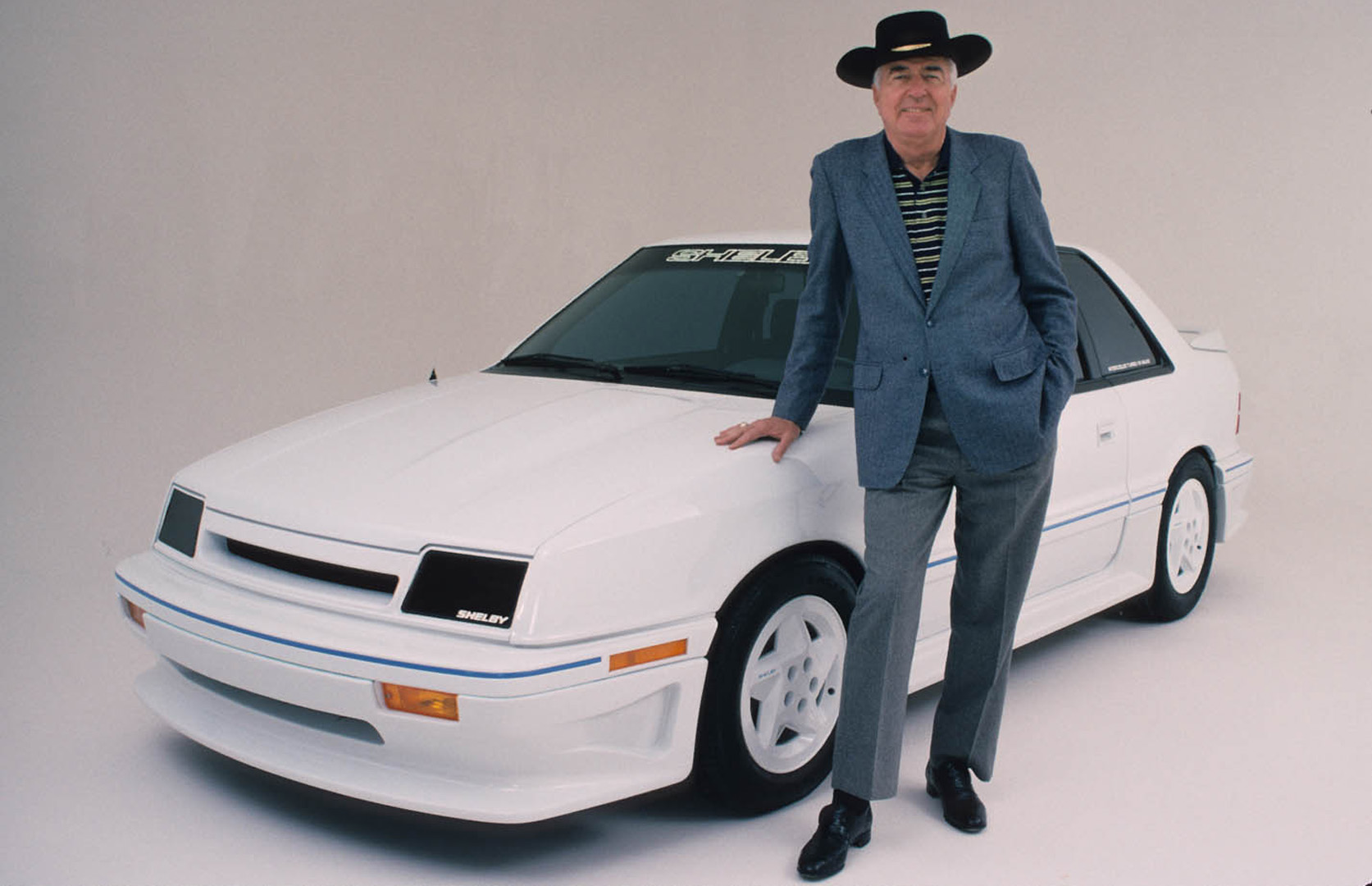Carroll Shelby posing with a white car